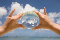 Saipan. One hands is holding a glass sphere and it projects the sky and the clouds at the beach.