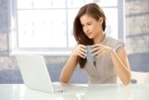 8604028-beautiful-smiling-businesswoman-at-work-looking-at-laptop-computer-screen-having-tea